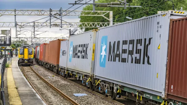 Container train passes London Midland commuter service in railway station